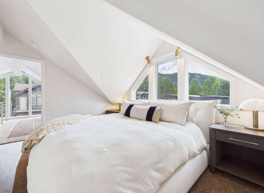 Experience serene mountain living in this charming bedroom, featuring a cozy bed adorned with plush white linens and a textured throw.