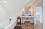 This bright and airy bathroom features a deep soaking tub perfect for relaxation, complemented by a sleek vanity with a modern vessel sink.