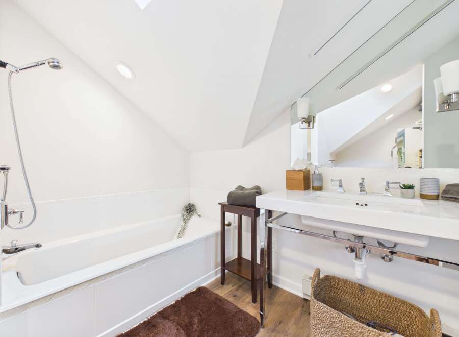 This bright and airy bathroom features a deep soaking tub with a modern shower head, perfect for unwinding after a long day.
