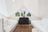 Experience breathtaking mountain views from this charming attic bedroom, featuring two cozy beds and a unique triangular window.