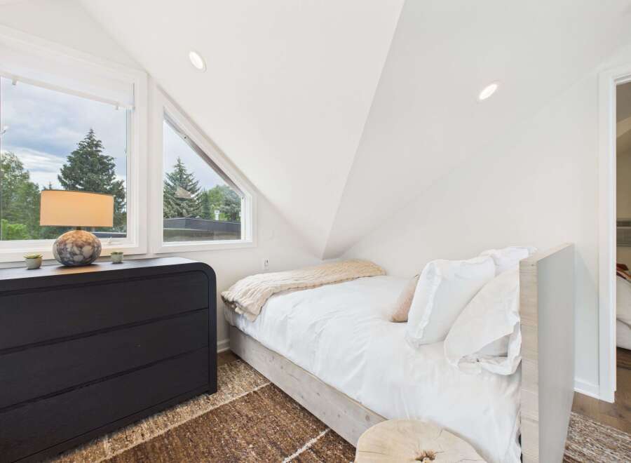 Discover this charming bedroom featuring a comfortable bed with crisp white linens and a cozy throw blanket.