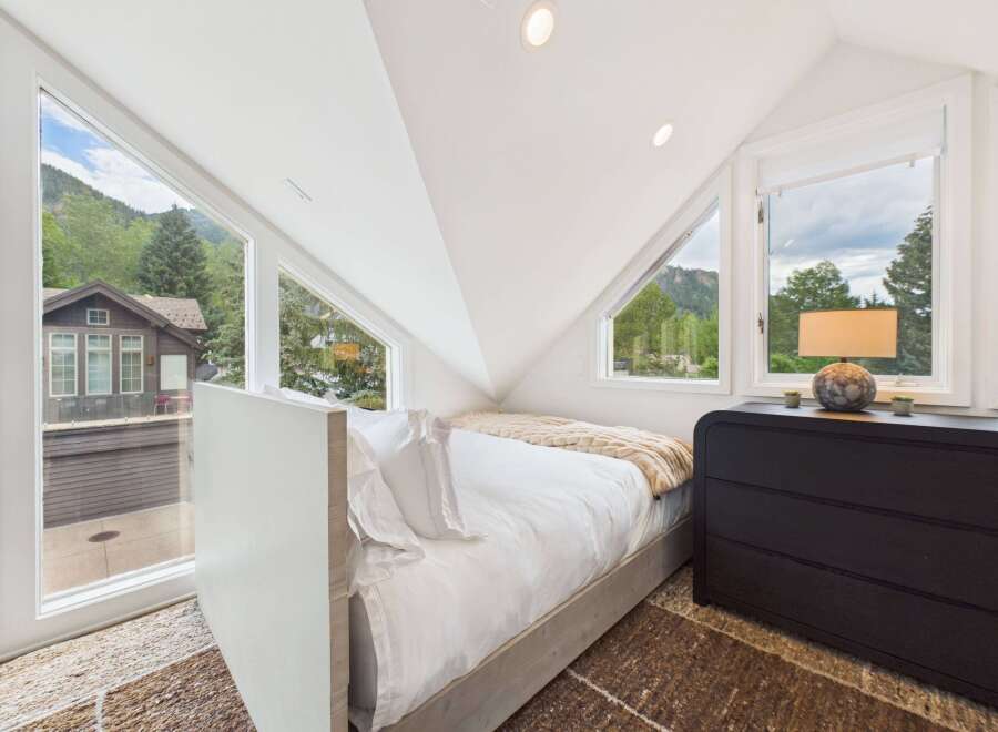 Experience breathtaking mountain views from this unique bedroom, featuring a modern bed and a stylish dresser.