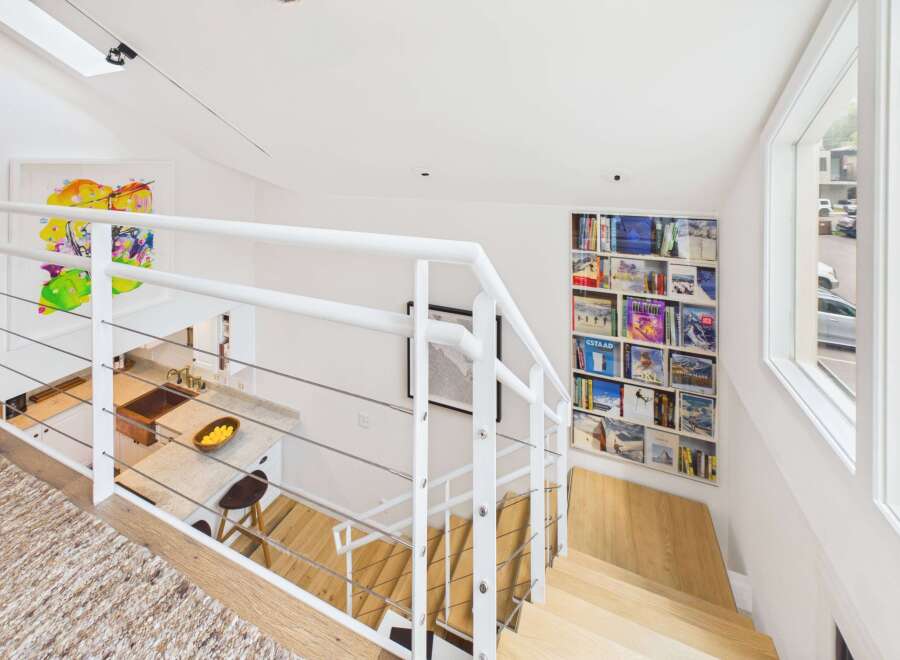Ascend to a modern oasis featuring a sleek white staircase with cable railings, leading to a bright open-concept living space.