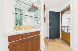 Step into this charming entryway featuring a mirrored bar area with ample glassware and a wooden cabinet for storage.