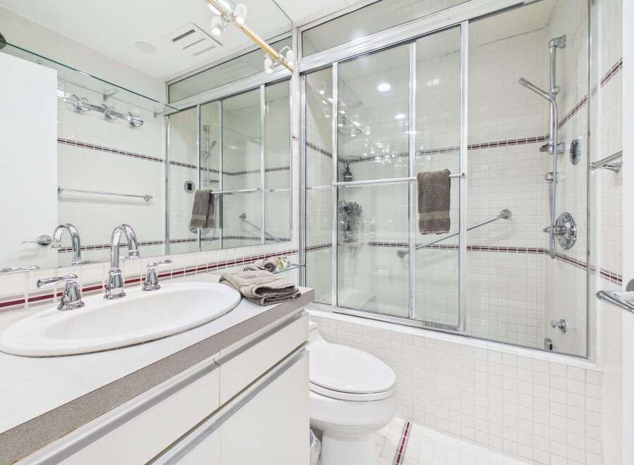 This modern bathroom features a sleek vanity with a double sink and chrome fixtures, complemented by a spacious glass-enclosed shower.
