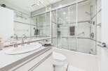 This modern bathroom features a sleek vanity with a double sink and chrome fixtures, complemented by a spacious glass-enclosed shower.