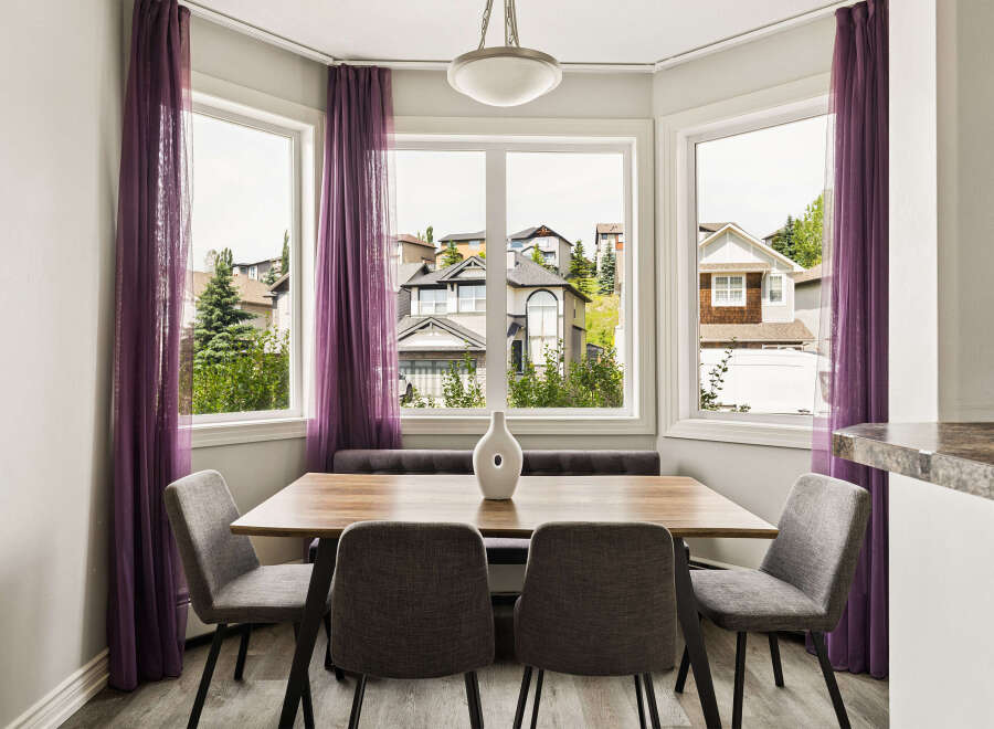Enjoy bright and airy meals in this charming dining nook, featuring a sleek wooden table and comfortable upholstered chairs.
