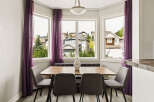 Enjoy bright and airy meals in this charming dining nook, featuring a sleek wooden table and comfortable upholstered chairs.