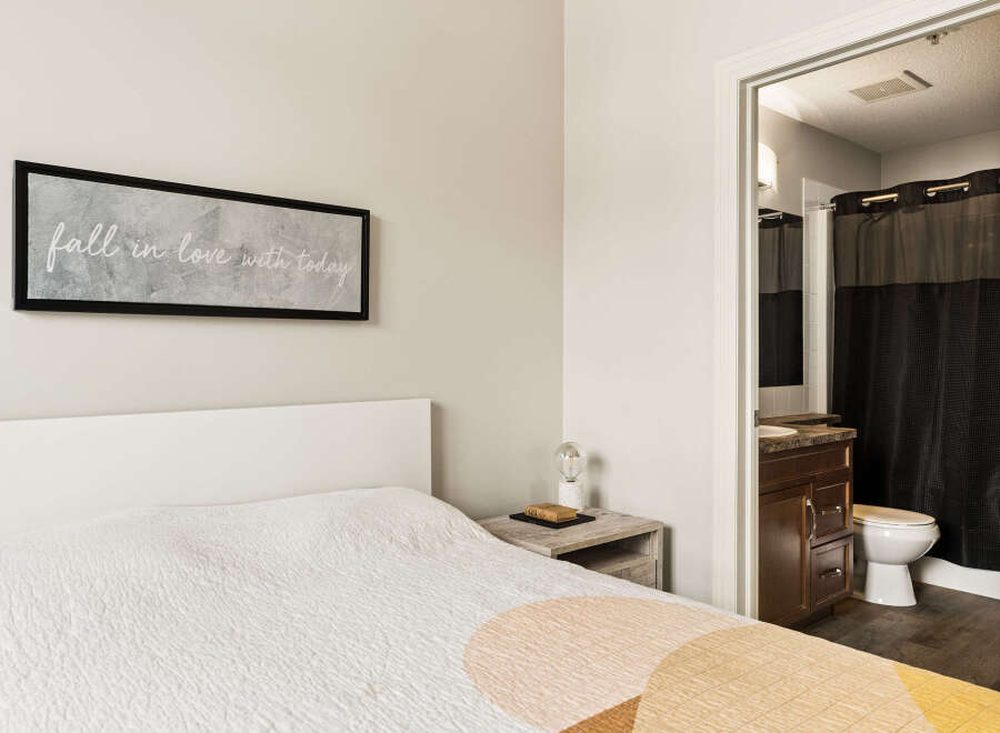 This inviting bedroom features a comfortable bed with a textured quilt and a modern white headboard.