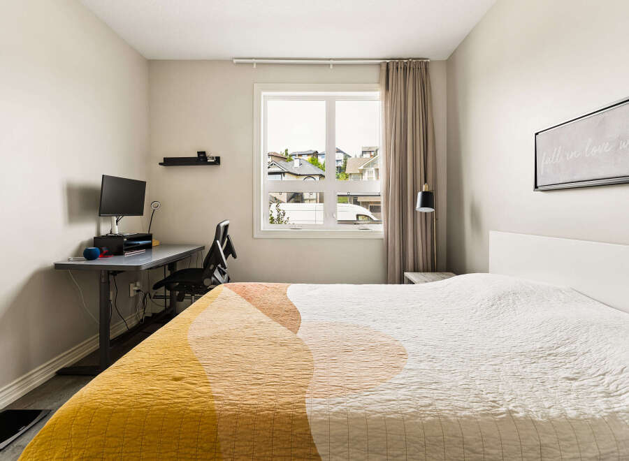 This bedroom offers a comfortable and functional space, featuring a cozy bed with a modern abstract quilt.