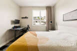 This bedroom offers a comfortable and functional space, featuring a cozy bed with a modern abstract quilt.