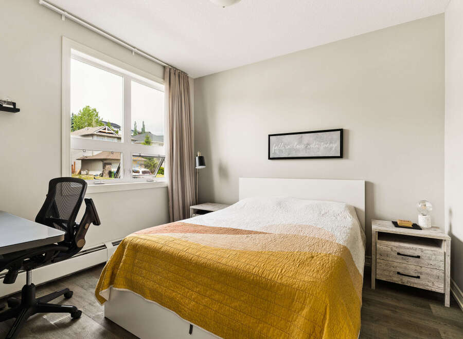 This bright and airy bedroom features a comfortable queen-size bed with a stylish striped quilt, perfect for relaxation.