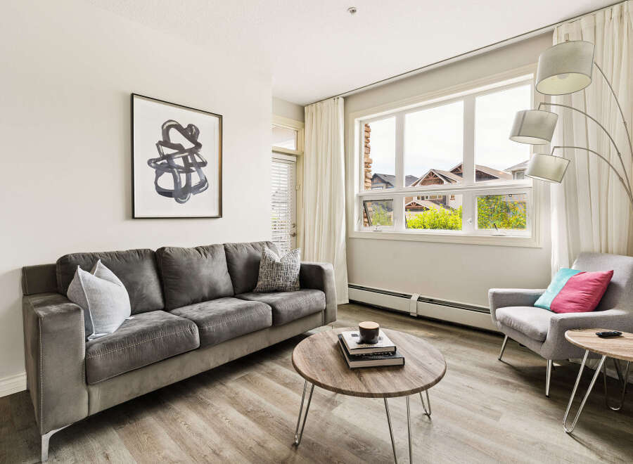 Step into this inviting living room, featuring a plush grey sofa adorned with decorative pillows, perfect for cozy evenings.