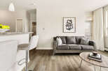 Experience modern living in this stylish apartment featuring a spacious living area with a comfortable grey sofa and a chic abstract art piece.