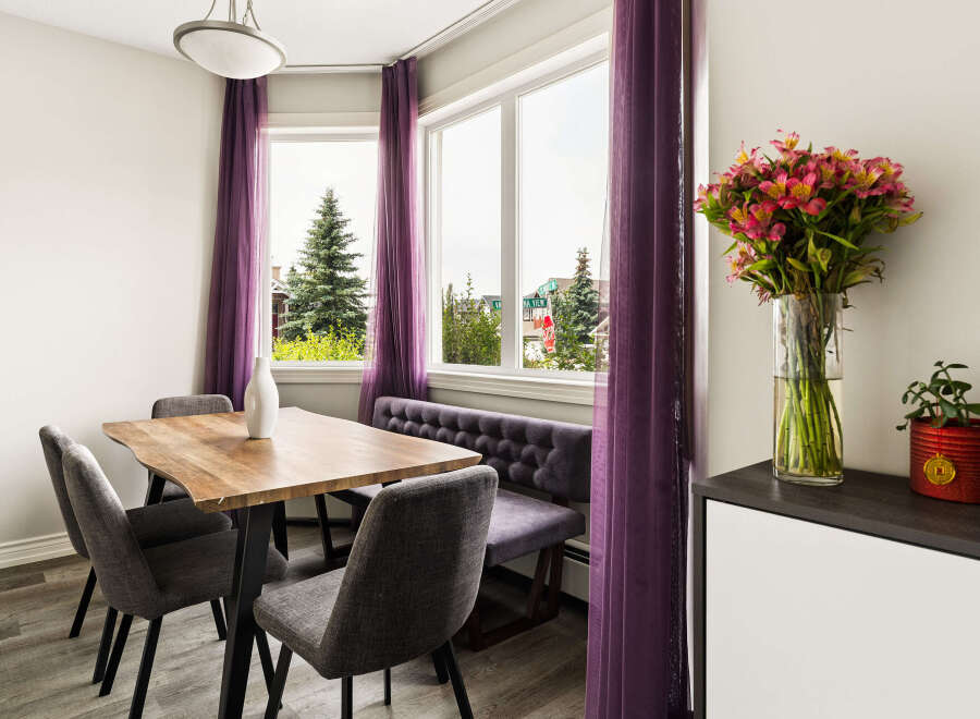 Brighten your dining experience in this charming space, featuring a rustic wooden table perfect for family meals.