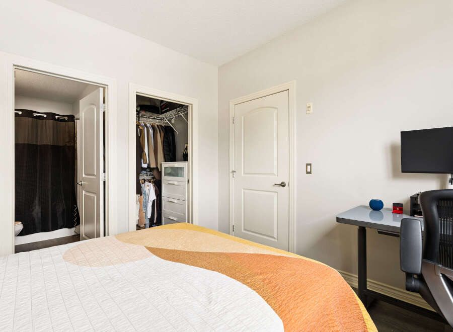 Discover comfort and convenience in this inviting bedroom, featuring a spacious walk-in closet with ample storage and an adjacent en-suite bathroom.