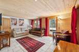 Experience cozy living in this charming room featuring a warm wooden ceiling and walls, complemented by a plush red rug.