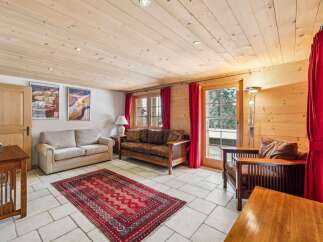 Experience cozy living in this charming room featuring a warm wooden ceiling and walls, complemented by a plush red rug.