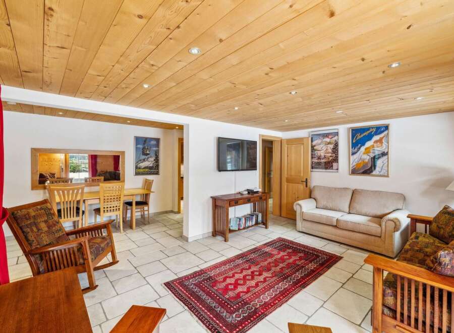 Experience cozy living in this charming mountain retreat, featuring a warm wooden ceiling and a spacious living area.