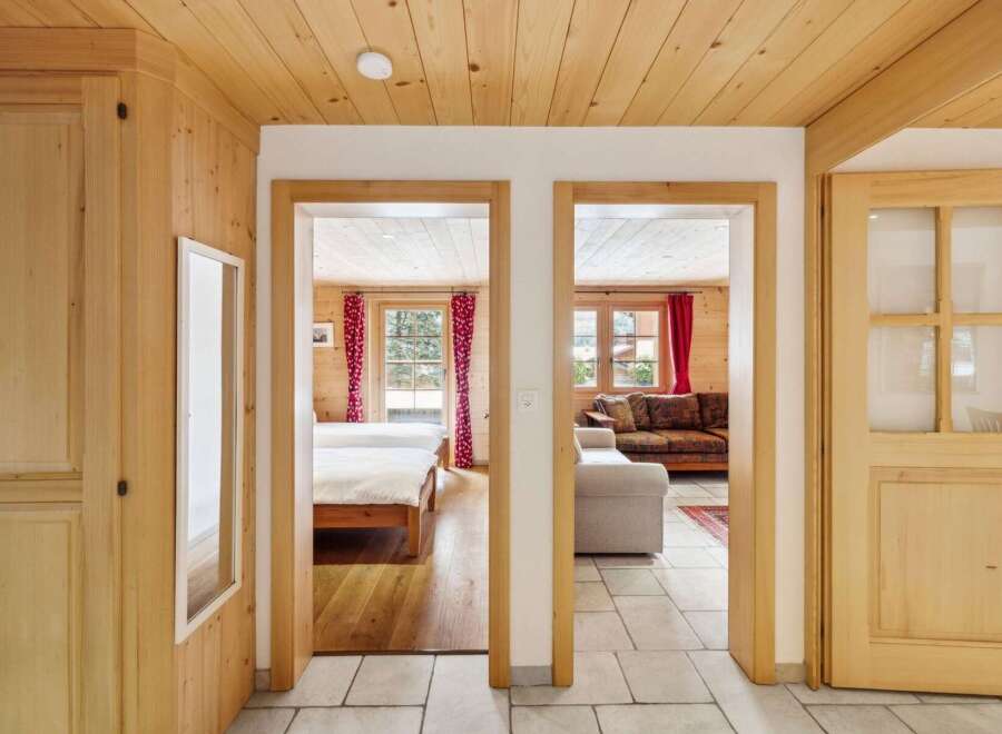 Step into a charming alpine retreat featuring a cozy living area with a plush sofa and a separate bedroom with two inviting beds.