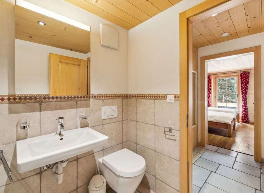 This charming bathroom features a modern wall-mounted sink and a clean white toilet, complemented by tiled walls and a decorative border.