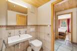 This charming bathroom features a modern wall-mounted sink and a clean white toilet, complemented by tiled walls and a decorative border.