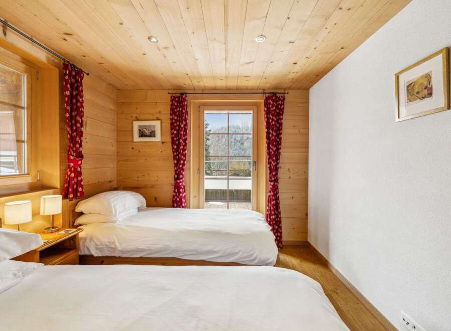 Experience cozy mountain living in this charming bedroom featuring two comfortable beds, perfect for families or friends.
