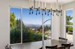 Experience breathtaking panoramic views from this stunning dining room, featuring expansive windows that showcase a vibrant landscape.