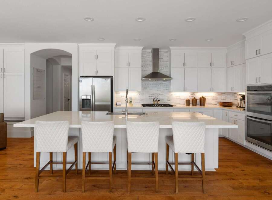 Experience luxury in this stunning modern kitchen, featuring sleek white cabinetry, a spacious quartz island with bar seating, and high-end stainless steel appliances.