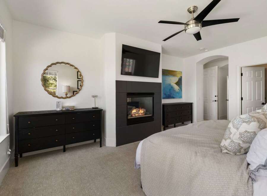 Experience luxury living in this master bedroom, featuring a modern gas fireplace and a wall-mounted television for ultimate relaxation.