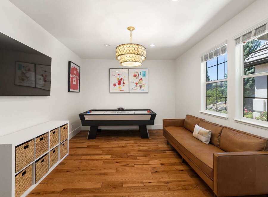 Enjoy endless entertainment in this stylish game room, featuring a sleek air hockey table and a comfortable leather sofa.