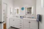 This modern bathroom features a spacious double vanity with a marble countertop, illuminated mirrors, and sleek chrome fixtures.