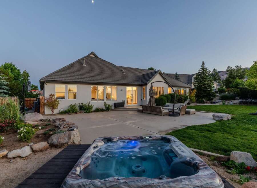 Experience ultimate relaxation in this stunning backyard oasis, featuring a luxurious hot tub perfect for unwinding under the evening sky.