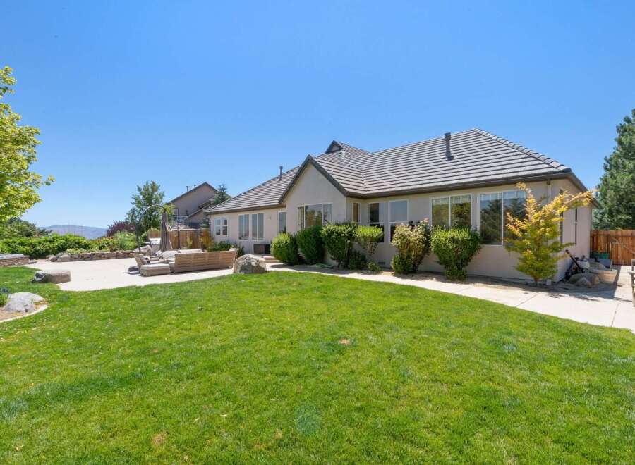 This spacious backyard offers a perfect blend of relaxation and entertainment, featuring a large concrete patio area with comfortable outdoor seating and a built-in hot tub.