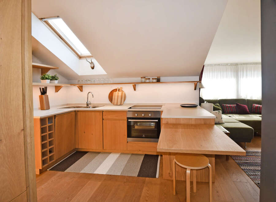 Discover this charming attic apartment featuring a modern, light wood kitchen with integrated appliances and a convenient breakfast bar.