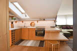 Discover this charming attic apartment featuring a modern, light wood kitchen with integrated appliances and a convenient breakfast bar.