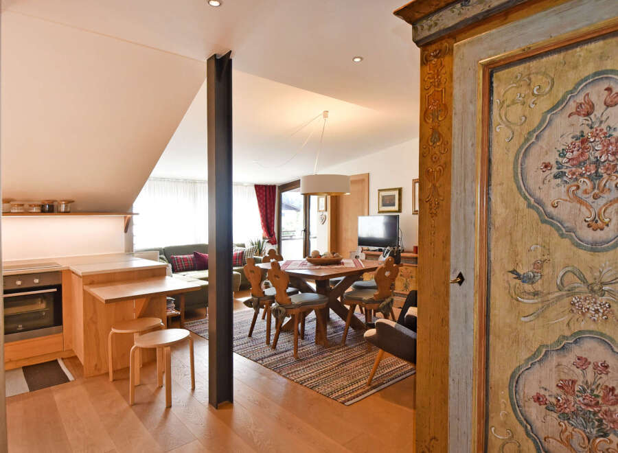 Discover this charming apartment featuring a cozy living area with a comfortable sofa and a rustic dining set perfect for family meals.