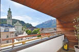 Experience breathtaking mountain views from this charming balcony, overlooking a picturesque town square with a historic church.