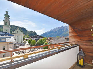 Experience breathtaking mountain views from this charming balcony, overlooking a picturesque town square with a historic church.
