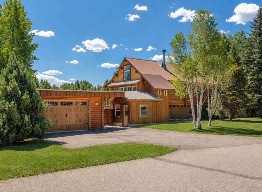Experience rustic charm in this stunning log home, featuring a spacious attached garage and a welcoming covered entryway.