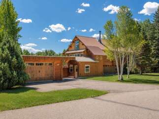 Experience rustic charm in this stunning log home, featuring a spacious attached garage and a welcoming covered entryway.