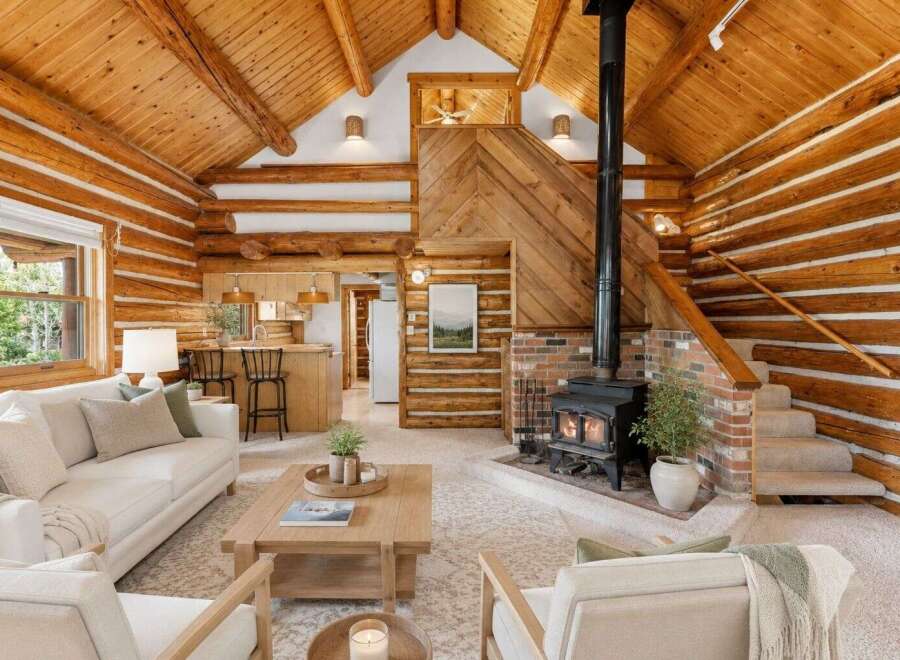 Experience rustic charm in this stunning log cabin living room, featuring a cozy fireplace and a beautiful wood-paneled ceiling.
