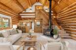 Experience rustic charm in this stunning log cabin living room, featuring a cozy fireplace and a beautiful wood-paneled ceiling.