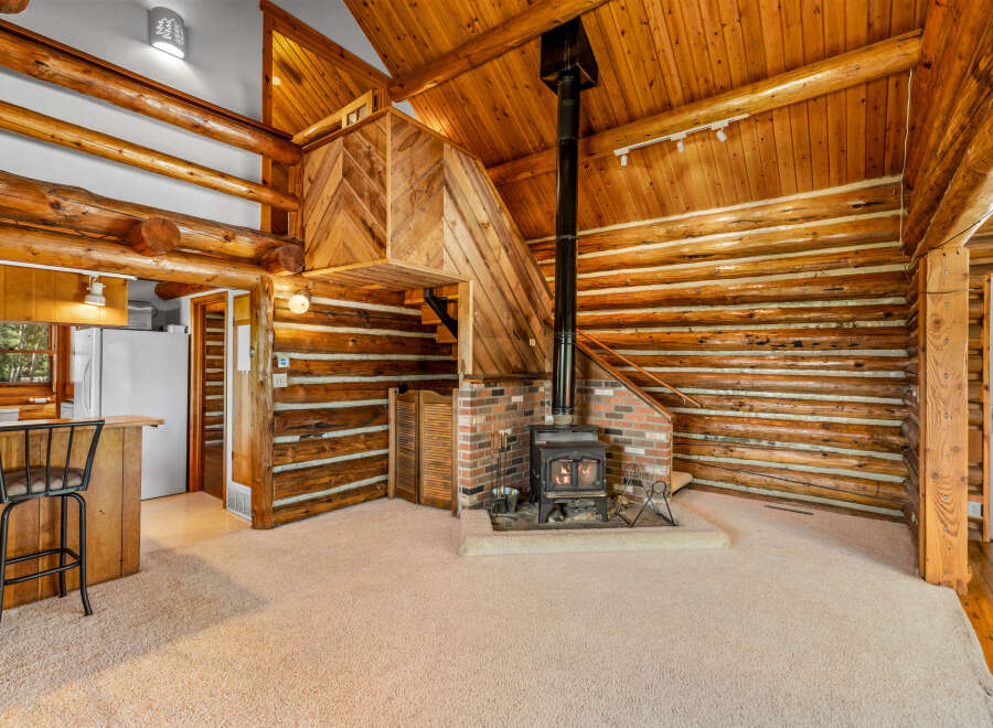 Experience rustic charm in this log cabin living space, featuring a cozy wood-burning stove as the focal point.
