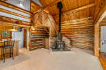 Experience rustic charm in this log cabin living space, featuring a cozy wood-burning stove as the focal point.