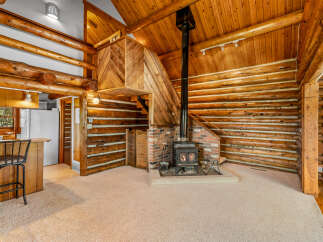 Experience rustic charm in this log cabin living space, featuring a cozy wood-burning stove as the focal point.