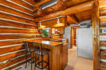 Experience rustic charm in this log cabin kitchen, featuring a cozy breakfast bar with two stools perfect for morning coffee.