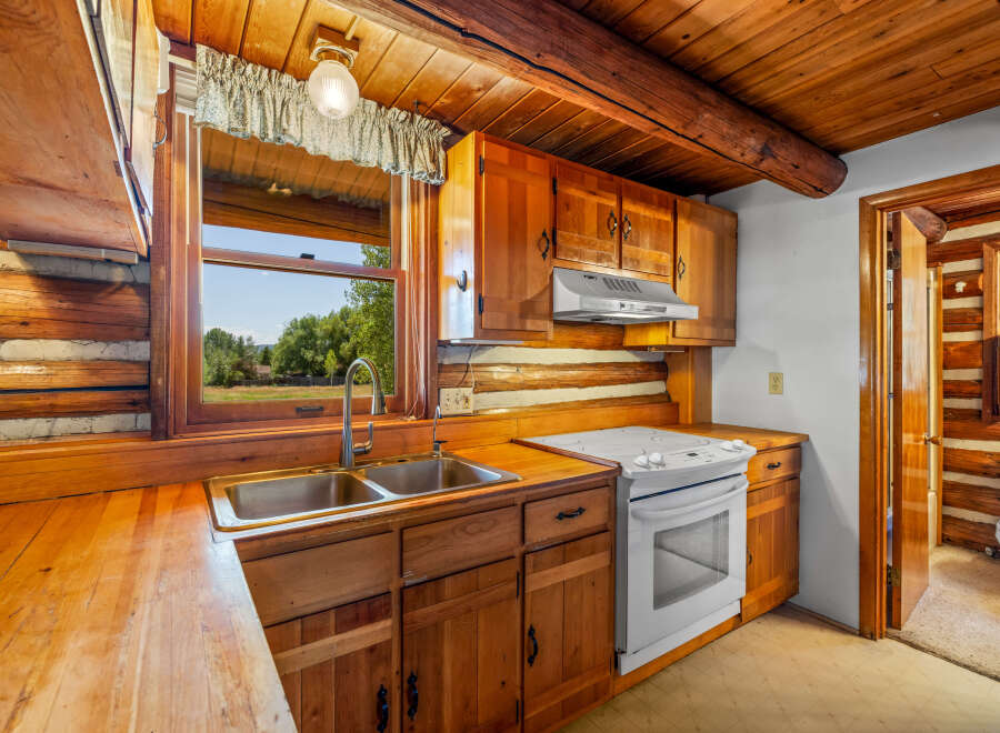 Experience rustic charm in this cozy log cabin kitchen, featuring warm wooden cabinetry and countertops.