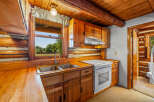 Experience rustic charm in this cozy log cabin kitchen, featuring warm wooden cabinetry and countertops.