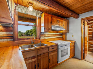Experience rustic charm in this cozy log cabin kitchen, featuring warm wooden cabinetry and countertops.